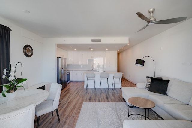 living room with ceiling fan, light wood-type flooring, and sink