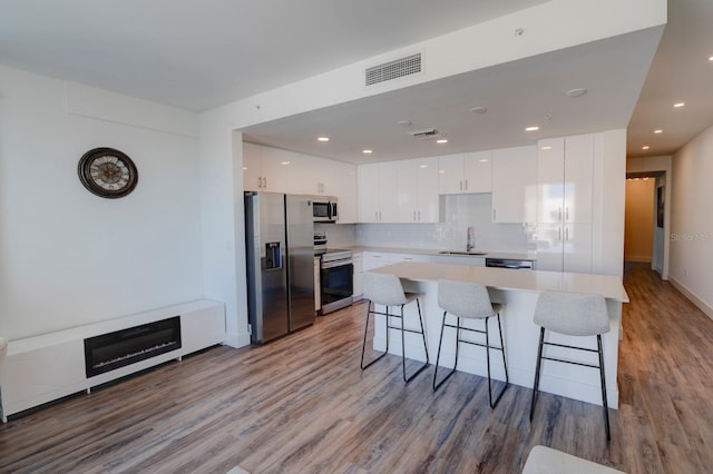 kitchen with light hardwood / wood-style floors, white cabinetry, sink, and appliances with stainless steel finishes