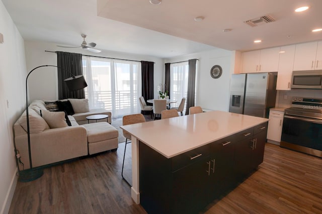 kitchen with white cabinets, a kitchen island, dark hardwood / wood-style flooring, and appliances with stainless steel finishes