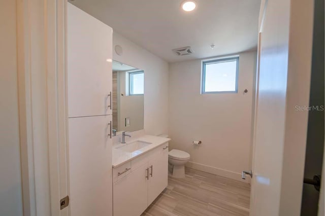 bathroom with hardwood / wood-style flooring, vanity, a healthy amount of sunlight, and toilet