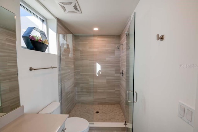 bathroom featuring vanity, a shower with shower door, and toilet