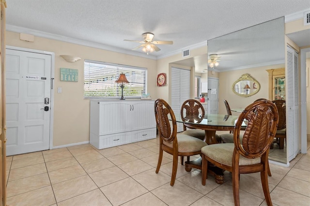 tiled dining space featuring a textured ceiling, ceiling fan, and crown molding