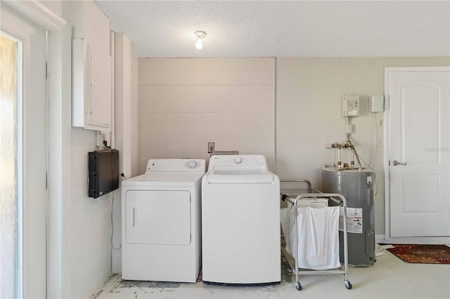 laundry room featuring independent washer and dryer, water heater, and a textured ceiling