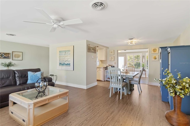 living room with light hardwood / wood-style flooring and ceiling fan