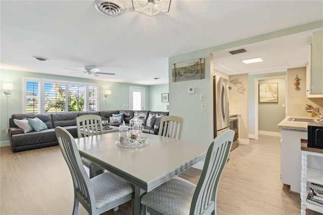 dining space featuring sink, ceiling fan, and light hardwood / wood-style flooring