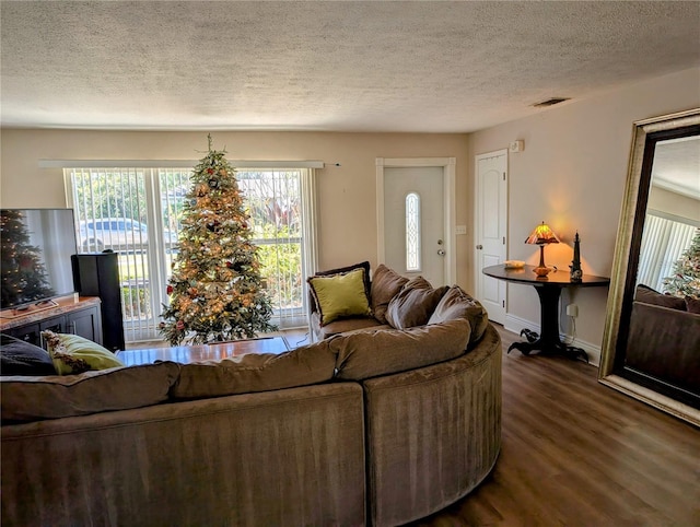 living room featuring a healthy amount of sunlight, dark hardwood / wood-style flooring, and a textured ceiling