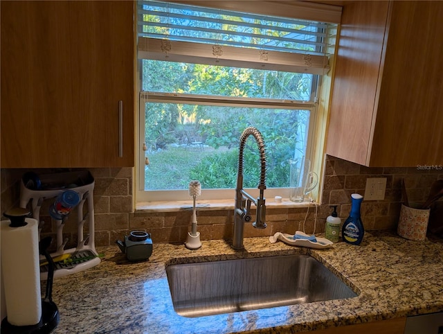 kitchen with light stone counters, sink, and tasteful backsplash