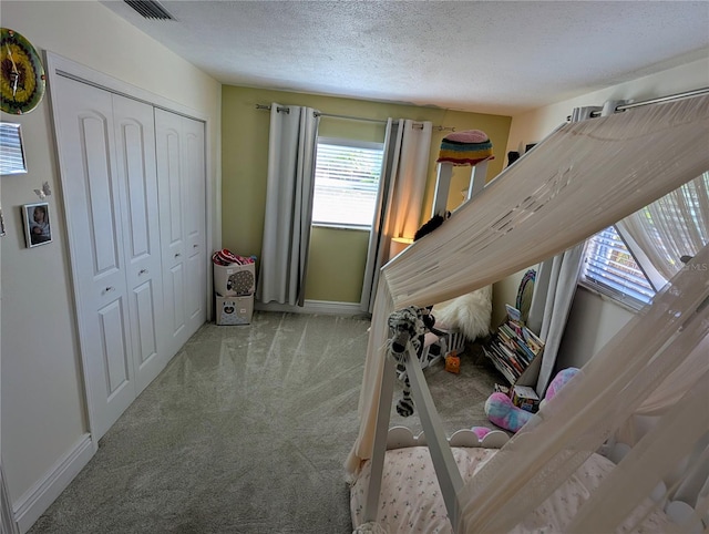 bedroom with carpet, a textured ceiling, and a closet