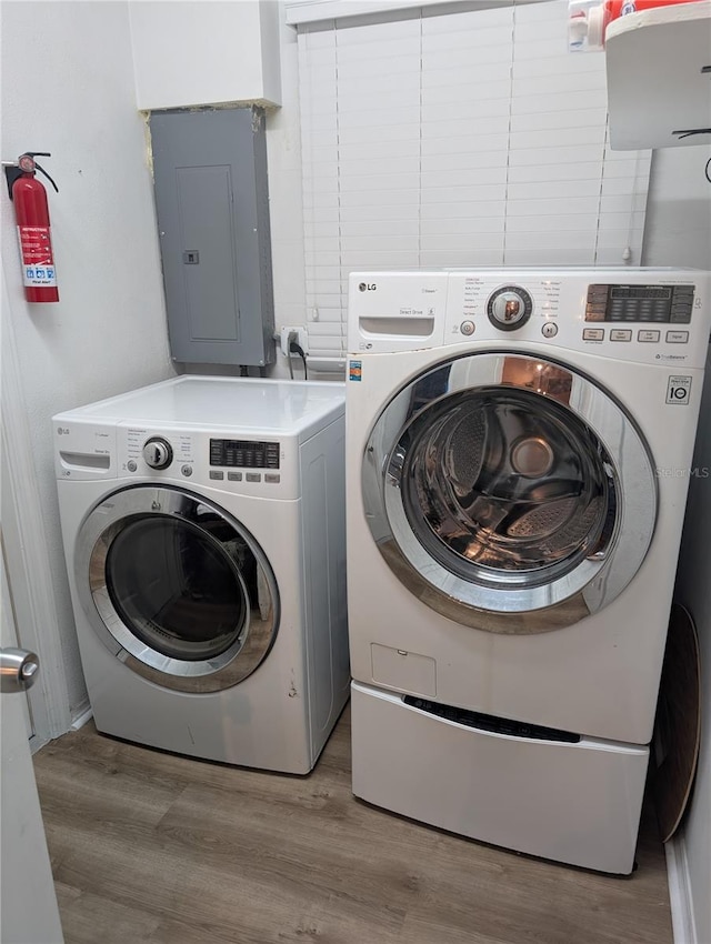 washroom featuring electric panel, separate washer and dryer, and light hardwood / wood-style floors