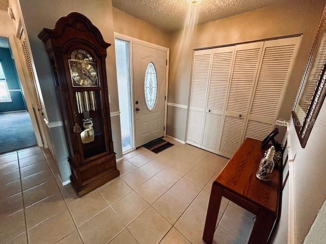 foyer entrance with a textured ceiling and light tile patterned floors