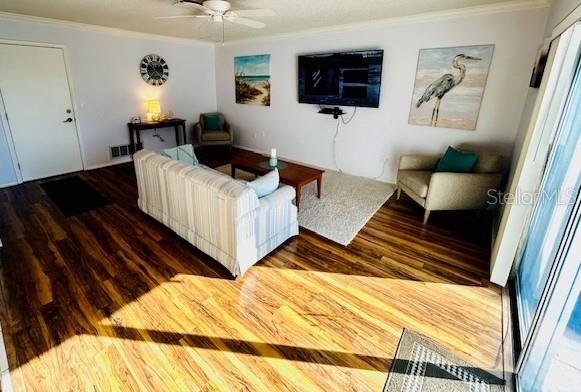 living room featuring dark hardwood / wood-style flooring, ornamental molding, and ceiling fan