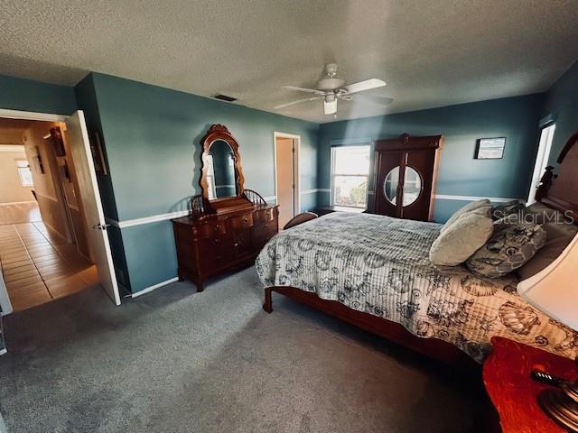 bedroom with carpet flooring, a textured ceiling, and ceiling fan