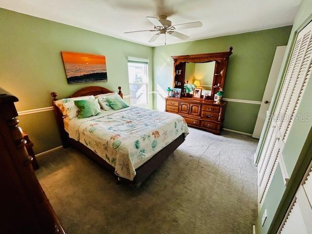 bedroom with a closet, ceiling fan, and carpet flooring