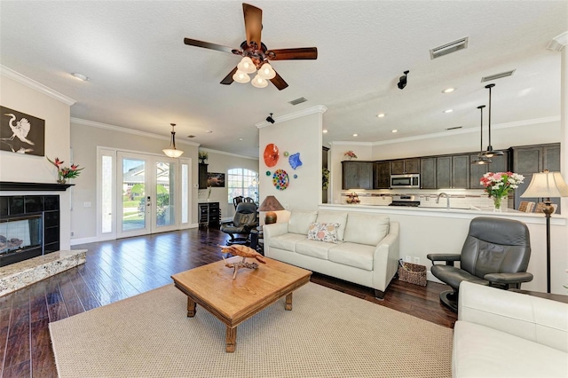 living room with ceiling fan, french doors, dark hardwood / wood-style flooring, a fireplace, and ornamental molding