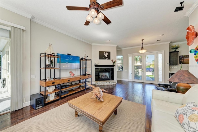 living room with ceiling fan, french doors, dark hardwood / wood-style flooring, a fireplace, and ornamental molding