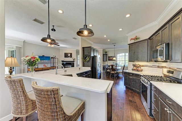 kitchen with a kitchen breakfast bar, dark hardwood / wood-style flooring, hanging light fixtures, and appliances with stainless steel finishes