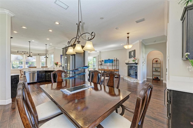 dining area with a textured ceiling, dark hardwood / wood-style flooring, and ornamental molding