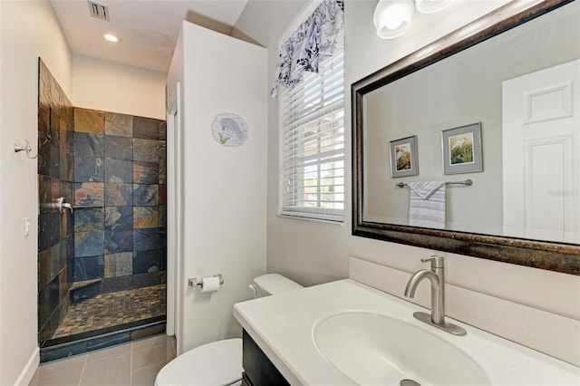 bathroom featuring a tile shower, vanity, toilet, and tile patterned floors