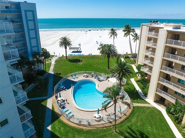 view of swimming pool featuring a view of the beach, a water view, and a patio area