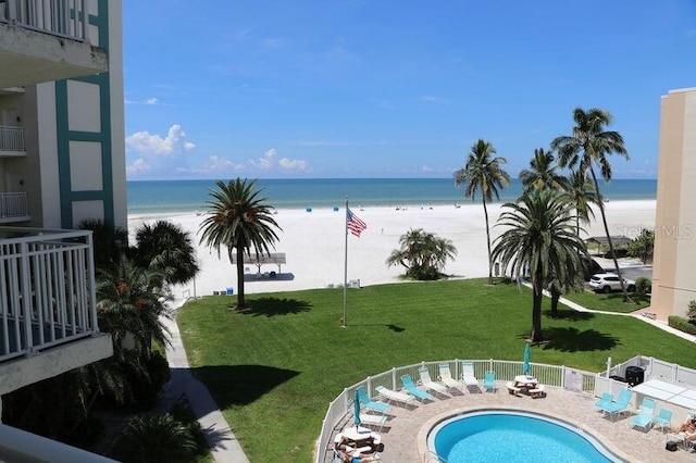 view of pool with a lawn, a water view, and a beach view