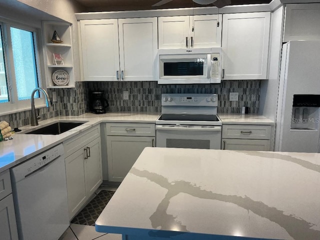 kitchen featuring tasteful backsplash, white cabinetry, sink, and white appliances