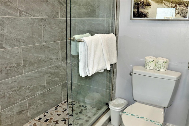 bathroom featuring toilet and a shower with shower door