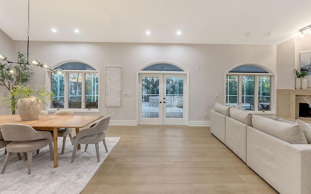 dining room featuring a fireplace, french doors, a chandelier, and light hardwood / wood-style flooring