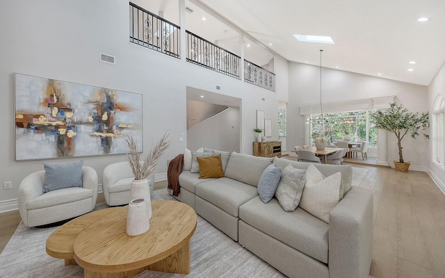 living room with light hardwood / wood-style floors and high vaulted ceiling