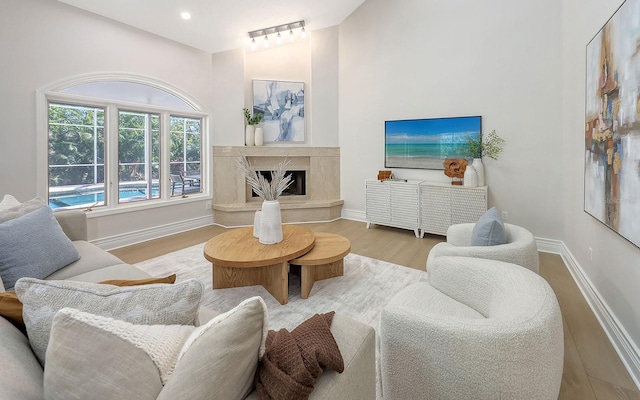 living room with a high end fireplace, light hardwood / wood-style floors, and high vaulted ceiling