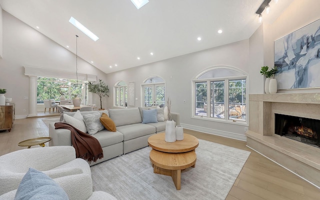 living room featuring light hardwood / wood-style flooring, high vaulted ceiling, and a healthy amount of sunlight