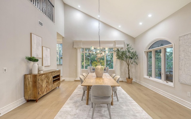 dining space with an inviting chandelier, high vaulted ceiling, and light hardwood / wood-style flooring