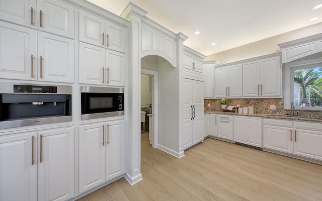 kitchen with sink, decorative backsplash, light wood-type flooring, white cabinetry, and stainless steel appliances