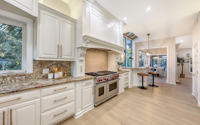 kitchen with white cabinetry, hanging light fixtures, light hardwood / wood-style floors, double oven range, and custom exhaust hood