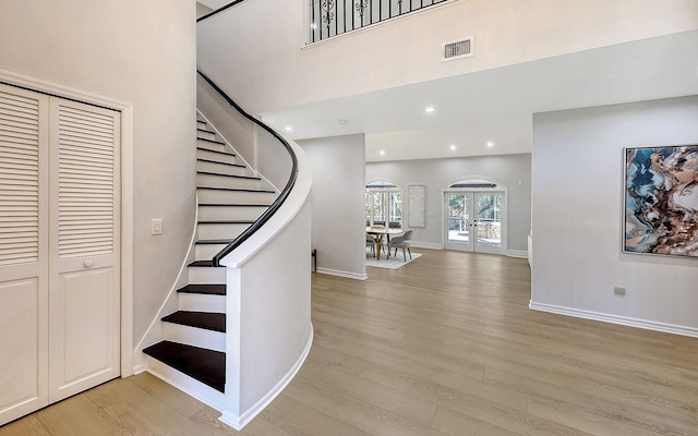 staircase with wood-type flooring, a high ceiling, and french doors