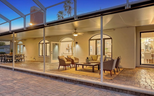 patio terrace at dusk with outdoor lounge area, ceiling fan, and a lanai