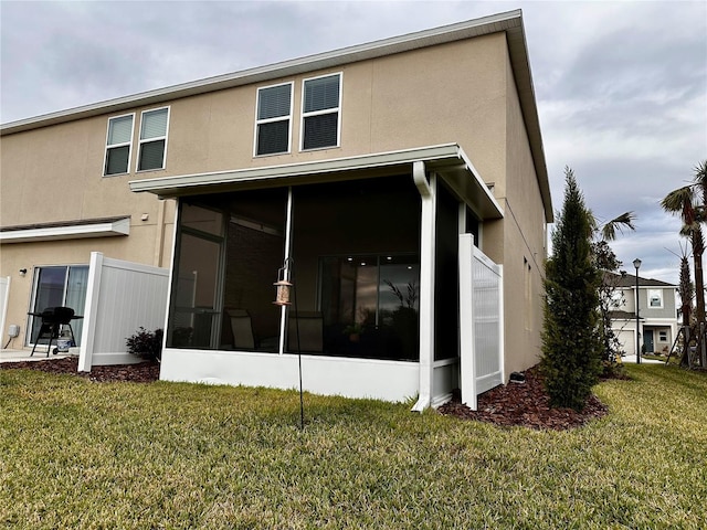 rear view of property with a lawn and a sunroom