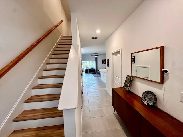 stairway featuring tile patterned flooring and ceiling fan