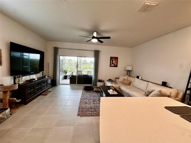 living room featuring light tile patterned floors, a textured ceiling, and ceiling fan