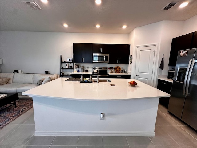 kitchen featuring a center island with sink, sink, light tile patterned floors, and stainless steel appliances