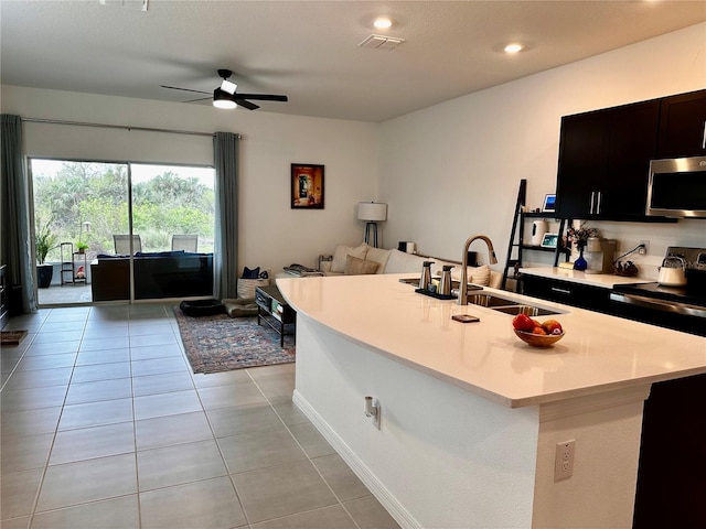 kitchen with a kitchen island with sink, range with electric cooktop, sink, ceiling fan, and light tile patterned floors