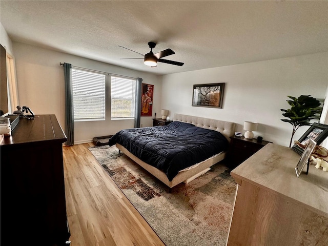 bedroom with a textured ceiling, light wood-type flooring, and ceiling fan