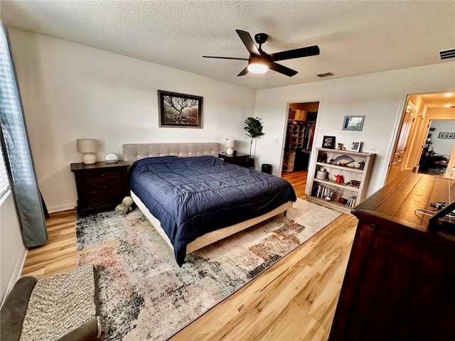 bedroom with ceiling fan, light hardwood / wood-style floors, a walk in closet, and a closet