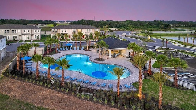 pool at dusk with a water view and a patio