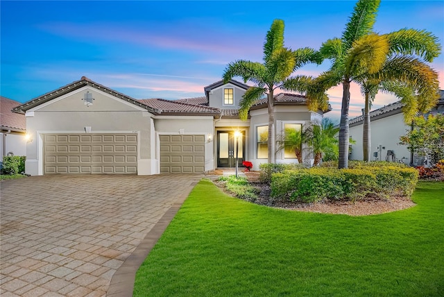 mediterranean / spanish home with a yard and a garage