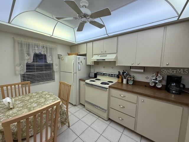 kitchen featuring wood counters, light tile patterned floors, white appliances, and ceiling fan