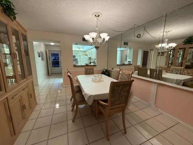 tiled dining space featuring a textured ceiling and a chandelier