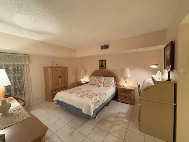 bedroom with light tile patterned floors and a textured ceiling