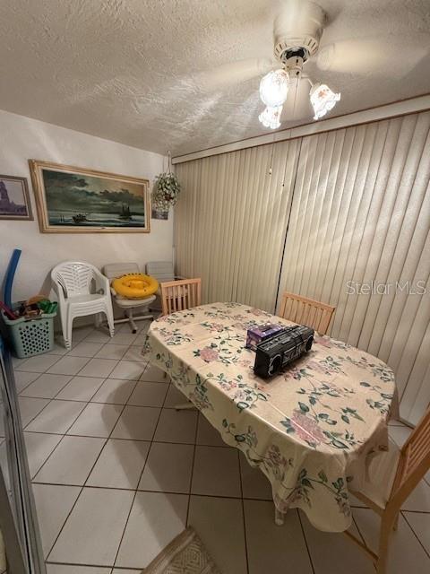 tiled dining room with ceiling fan and a textured ceiling