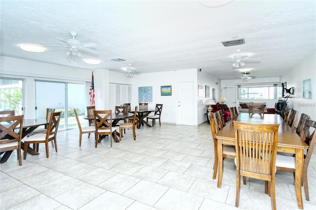 dining space featuring light tile patterned floors, a textured ceiling, and plenty of natural light