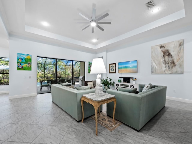 living room featuring ceiling fan and a raised ceiling